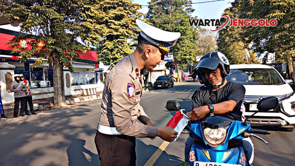 Polisi dan warga Jember mengibarkan bendera Merah Putih di jalan untuk sambut HUT RI ke-80